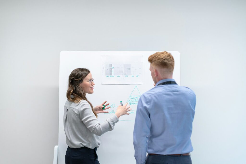 Dois profissionais planejando em quadro branco, representando o planejamento da gestão de exames periódicos