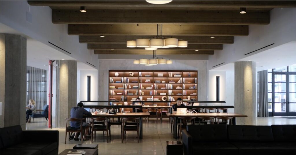 Biblioteca com estantes de livros e mesas de trabalho modernas, simbolizando o contraste entre a legislação trabalhista tradicional e os novos modelos de trabalho
