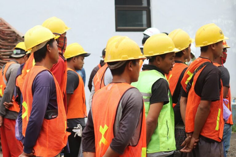 Grupo de trabalhadores com capacete e colete durante evento de segurança do trabalho, representando a SIPAT