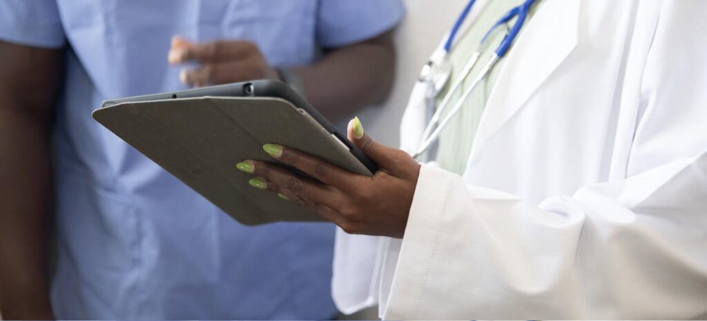 Profissional de saúde ocupacional analisando exame em tablet ao lado de outro profissional