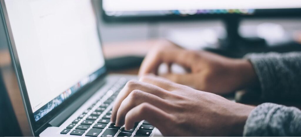 Mãos digitando em notebook, representando o preenchimento de eventos no eSocial