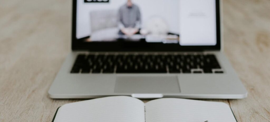 Notebook com videoaula em andamento sobre a mesa, representando treinamento de NR a distância